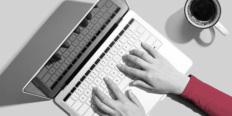 TMD employee working on their laptop, cup of coffee nearby